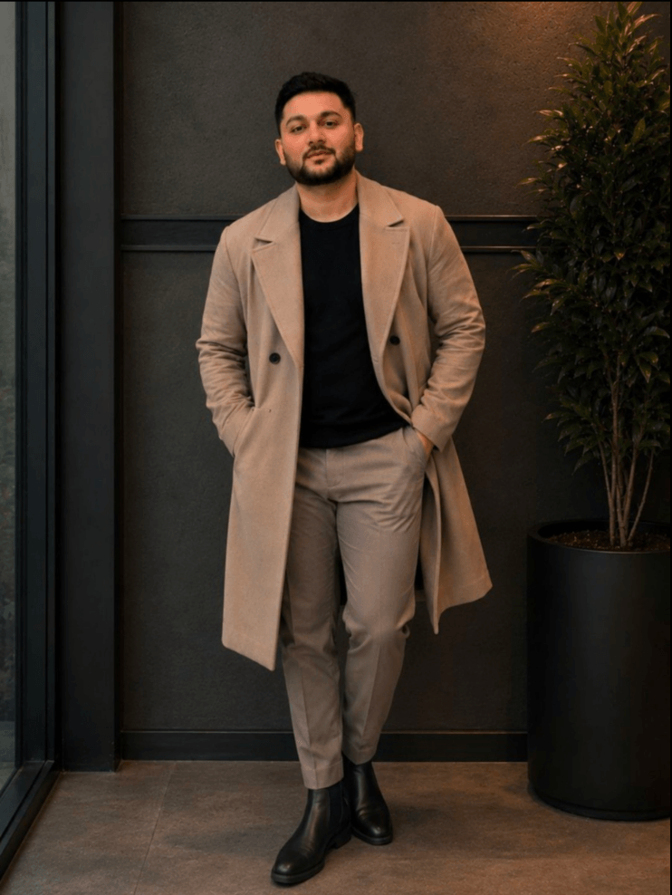 After: the same man wearing a beige overcoat, black tee and beige trousers